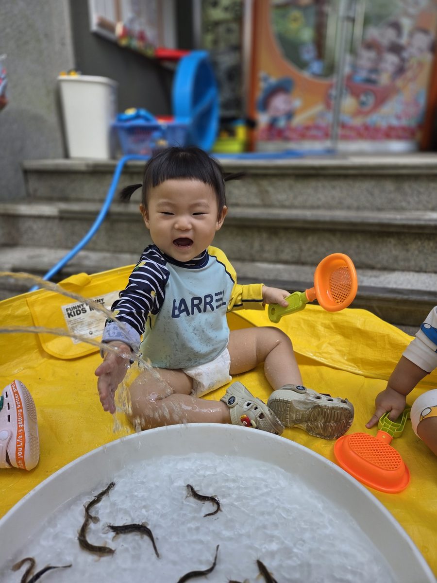 미꾸라지를 잡고 환하게 웃는 아이