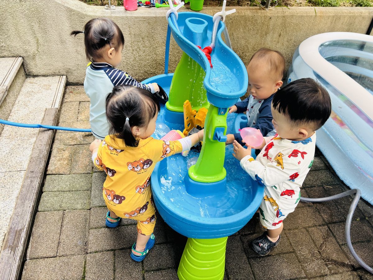 아이들이 물놀이 테이블에서 떨어지는 물줄기를 바라보며 놀이하는 모습