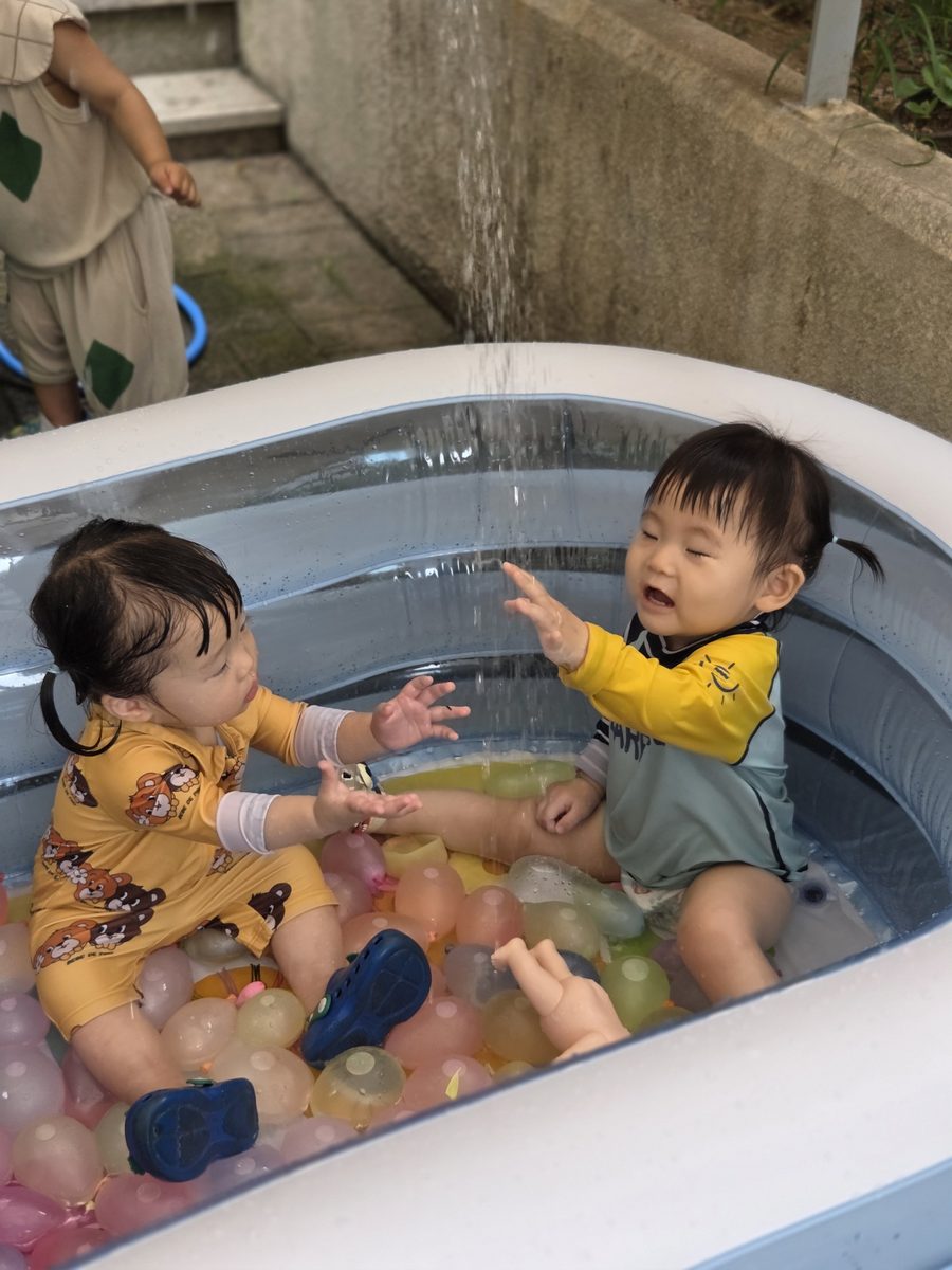 물놀이장에서 친구와 마주 보며 활짝 웃는 아이들