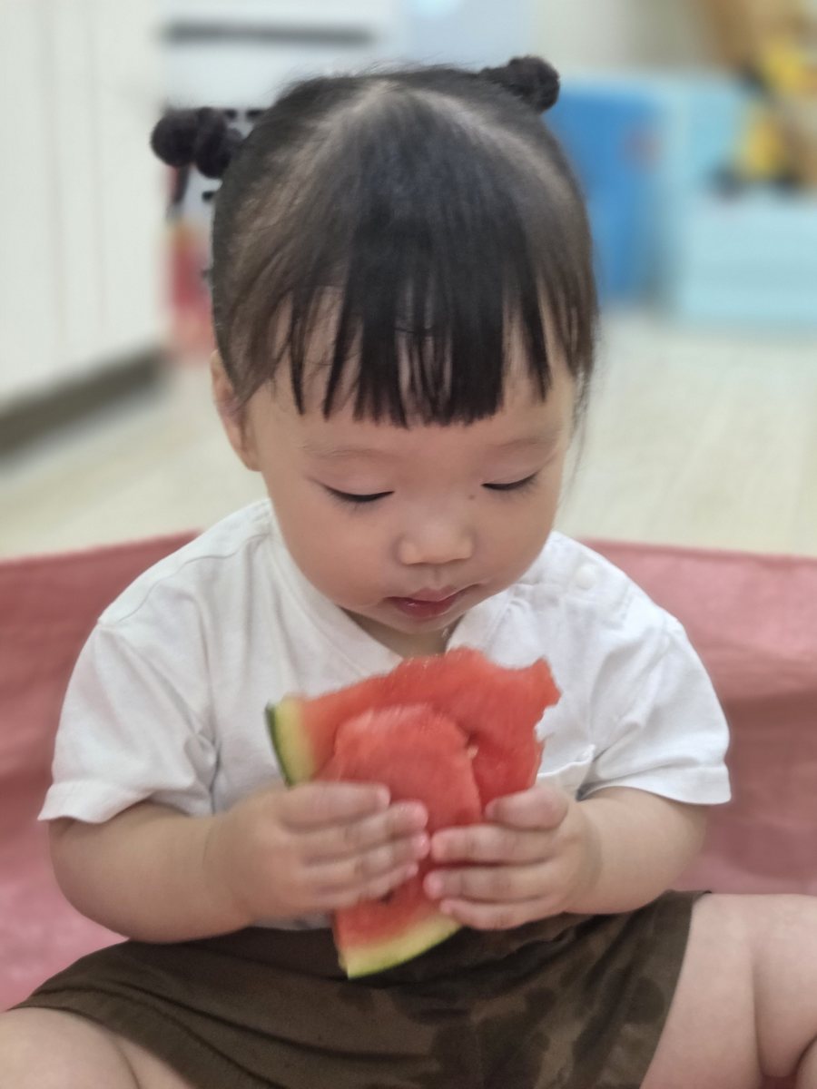 아이가 수박 조각을 손에 들고 살펴보는 모습