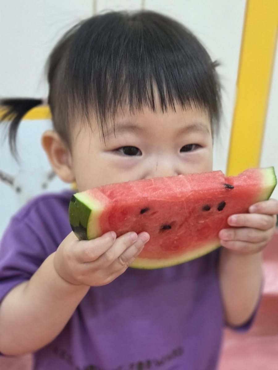 아이가 양손으로 수박을 들고 맛보는 모습
